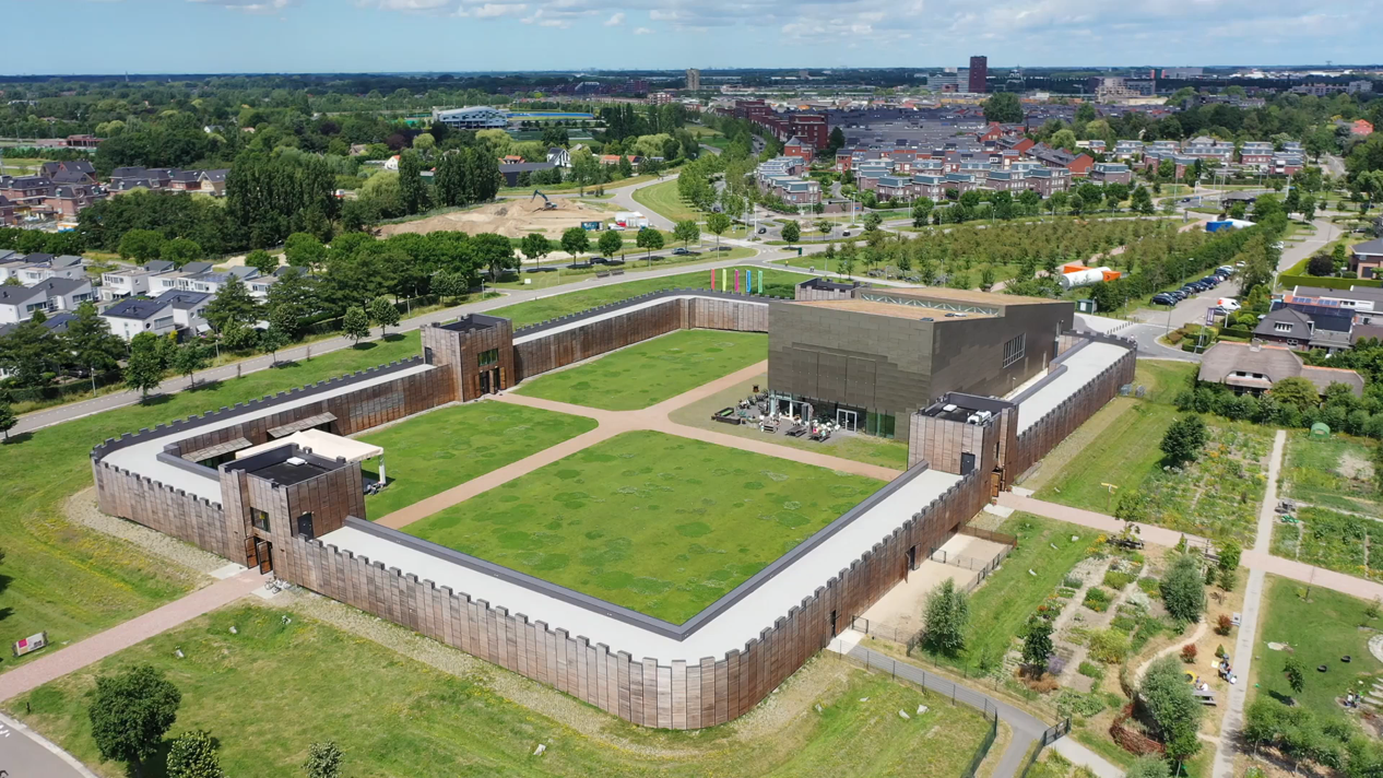 "Exterior view of Castellum Hoge Woerd, a reconstructed Roman fort in Utrecht, featuring stone walls and historical architectural elements under a partly cloudy sky."