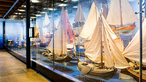 Exhibition at the Scheepvaartmuseum Amsterdam featuring maritime artifacts, ship models, and interactive displays in a historic naval setting

